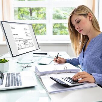 Young Businesswoman Calculating Bill With Computer And Laptop On Desk