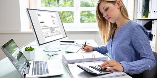 Young Businesswoman Calculating Bill With Computer And Laptop On Desk